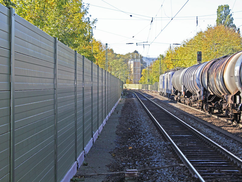 Lärmschutzwand an der ein Güterzug vorbeifährt