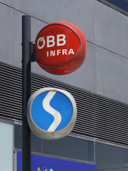 Logos der ÖBB Infra und der Straßenbahn, montiert auf einem Mast